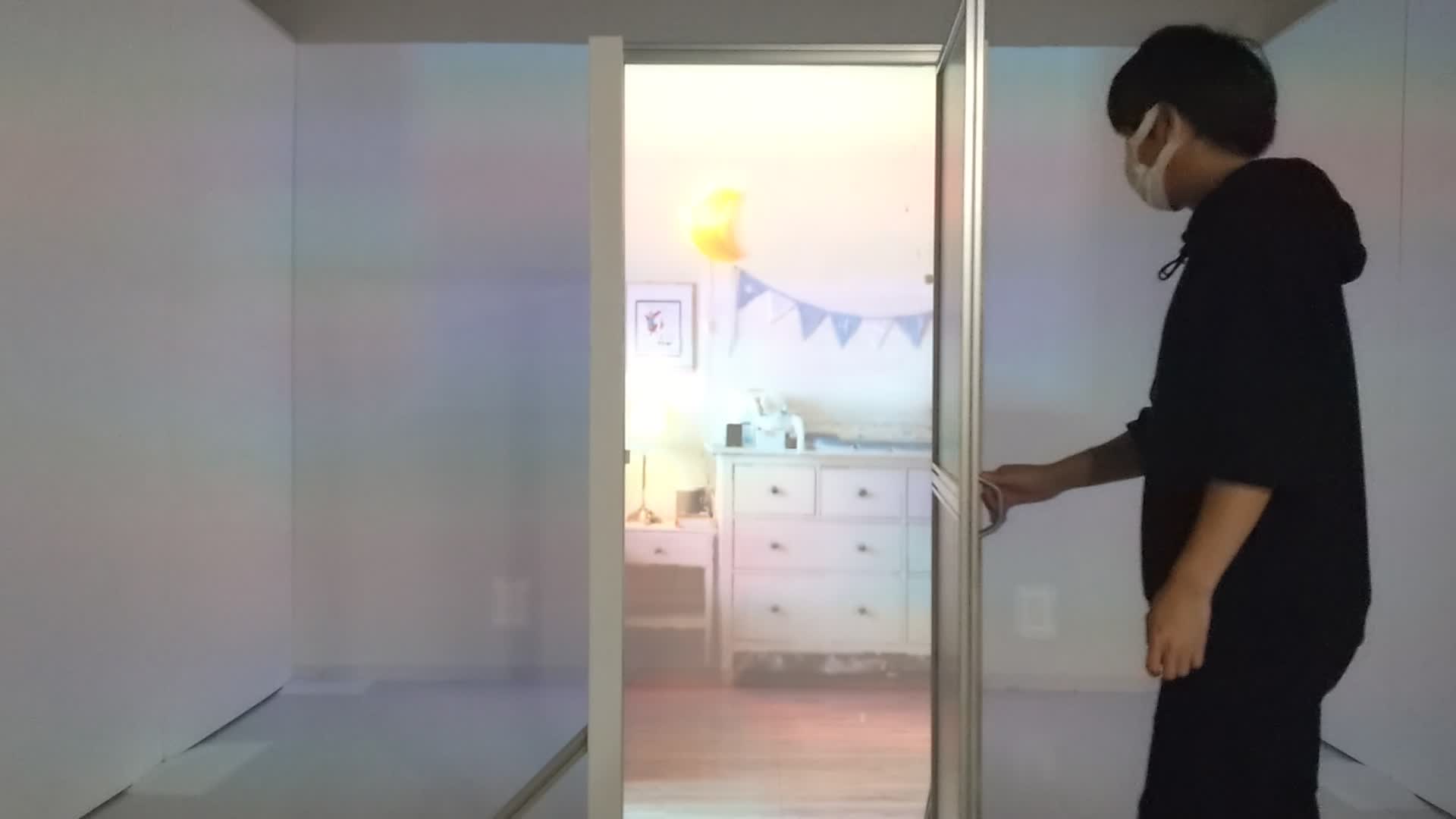 体験者が実物のドアを開き、その向こうに投影された家具のある部屋を見ている様子